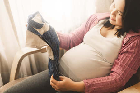 Pregnant woman feeling happy at home while taking care of her child. The young expecting mother...