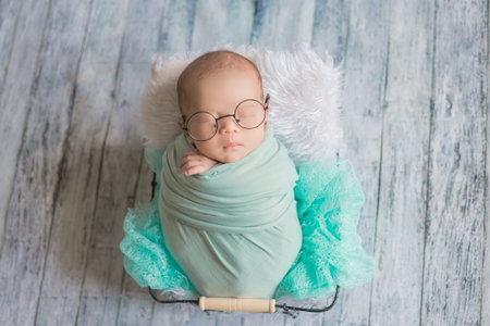 Adorable newborn baby sleeping in cozy room. Cute happy infant baby portrait with sleepy face in...