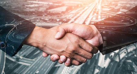 Double exposure image of business people handshake on city office building in background showing...
