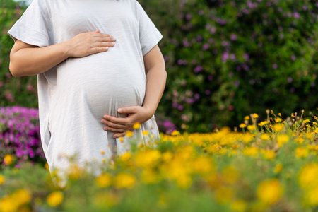 Pregnant woman feeling happy at home while taking care of her child. The young expecting mother...