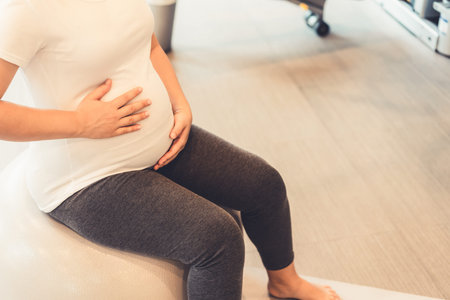 Active pregnant woman exercise in fitness center at yoga room. The young expecting mother holding...