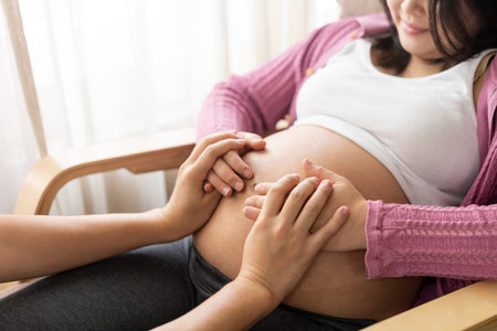 Pregnant couple of husband and wife feels love and relax at home. Young expecting woman holds baby...