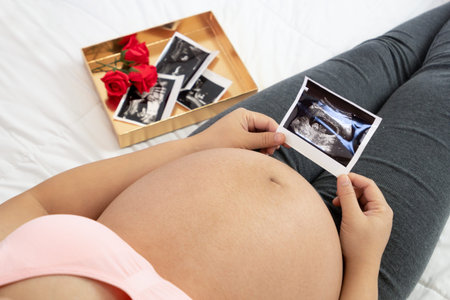 Pregnant woman feeling happy at home while taking care of her child. The young expecting mother...