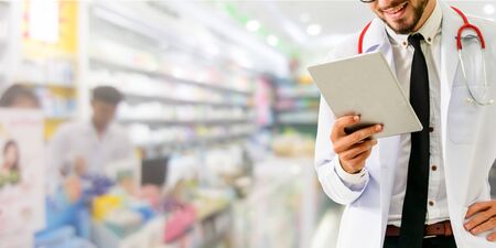 Pharmacist using tablet computer at the pharmacy. Medical healthcare and pharmaceutical staff service.の写真素材