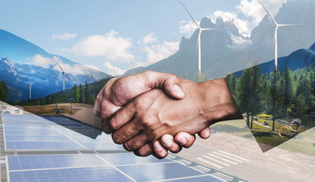 Double exposure graphic of business people handshake over wind turbine farm and green renewable...
