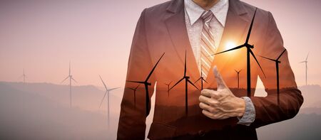 Double exposure graphic of business people working over wind turbine farm and green renewable energy worker interface. Concept of sustainability development by alternative energy.の写真素材