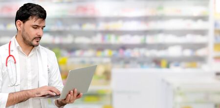Pharmacist or doctor using laptop computer at the pharmacy room. Medical healthcare and pharmaceutical staff service.の写真素材