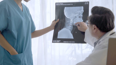 Doctor and nurse discuss on surgery result showing on x-ray film image of patient head. Concept of...