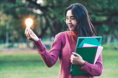 Creative young woman hold shinning light bulb. Concept of knowledge, intelligence and inspiration.の写真素材