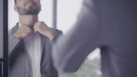 Man in formal business suit or groom costume getting dressed in dressing room preparing for working,...