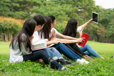 Team of young students studying in a group project in the park of university or school. Happy learning, community teamwork and youth friendship concept.の写真素材
