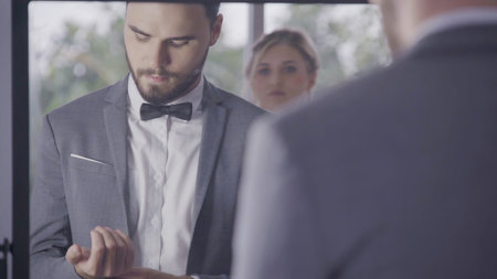 Man in formal business suit or groom costume getting dressed in dressing room preparing for working, engagement or wedding ceremony.の写真素材