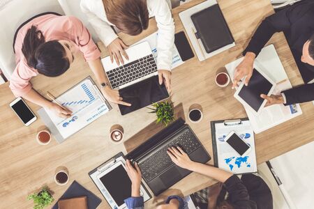 Top view of businessman executive in group meeting with other businessmen and businesswomen in modern office with laptop computer, coffee and document on table. People corporate business team concept.の写真素材