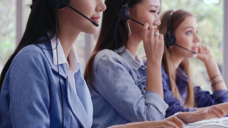 Customer support agent or call center with headset works on desktop computer while supporting the customer on phone call. Operator service business representative concept.の写真素材