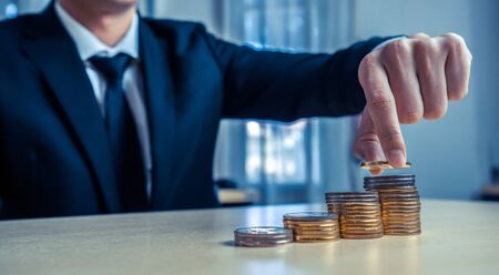 Businessman working with coin money currency. Concept of investment growth and money saving.の写真素材