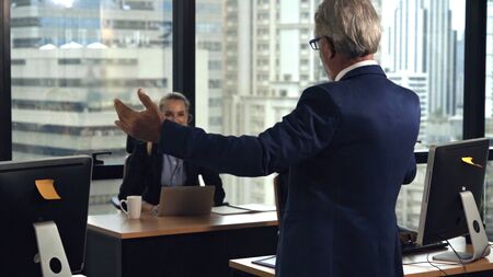 Senior leader giving advice speech to team members. Creative business people meeting at table in modern office. Multicultural business team.の写真素材