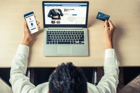 Young man use credit card for shopping payment online on laptop computer application or website. E-commerce and online shopping concept.の写真素材