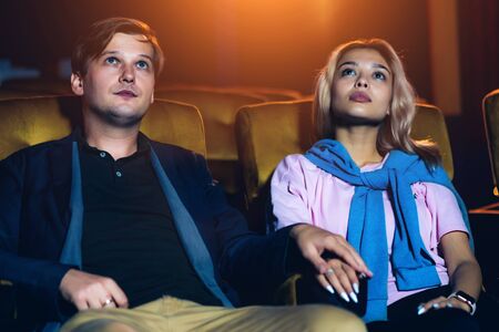 Caucasian lover enjoying to watch movie and eating popcorn together in the cinemaの写真素材