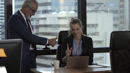 Senior manager gives advice to young woman worker in modern office. Leadership and training concept.の写真素材