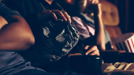 A man is secretly filming a video while watching a movie at the cinema