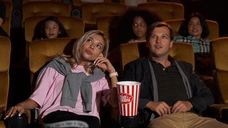 Audience walking to seats in the movie theater, watching film and eating popcorn.