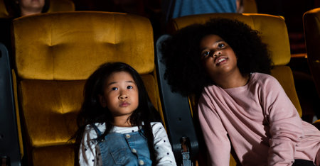 Two children african and asian having fun and enjoy watching movie in cinema