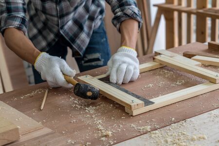 Carpenter working on wood craft at workshop to produce construction material or wooden furniture. The young Asian carpenter use professional tools for crafting. DIY maker and carpentry work concept.の写真素材
