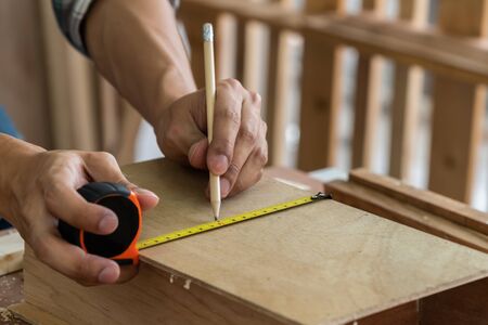 Carpenter working on wood craft at workshop to produce construction material or wooden furniture. The young Asian carpenter use professional tools for crafting. DIY maker and carpentry work concept.の写真素材