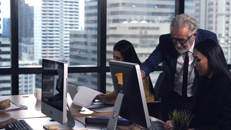 Senior manager gives advice to young woman worker in modern office. Leadership and training concept.
