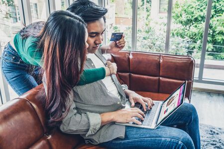 Young couple use credit card for online shopping on internet website at home. Number on the credit card is mock up. No personal information shown on the credit card. Online business shopping concept.の写真素材