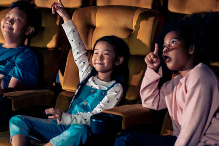 Three children having fun and enjoy watching movie in cinemaの写真素材