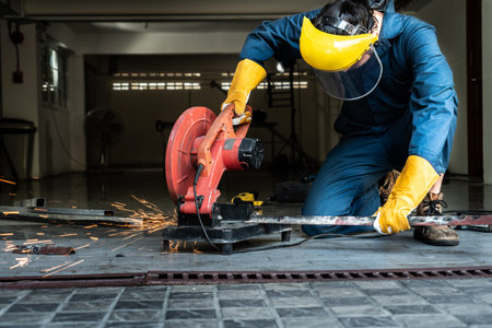 Professional mechanic is cutting steel metal with rotating diamond blade cutter. Steel industry and...