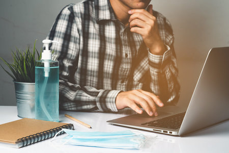 Coronavirus disease or COVID-19 protection concept - Young man work in office room at home with...