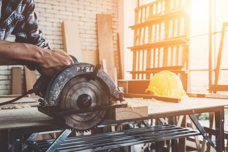 Carpenter working on wood craft at workshop to produce construction material or wooden furniture. The young Asian carpenter use professional tools for crafting. DIY maker and carpentry work concept.の写真素材