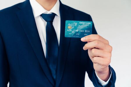 Portrait of businessman holding a credit card showing front view to the camera in close up view. Online shopping business and cashless payment concept.の写真素材