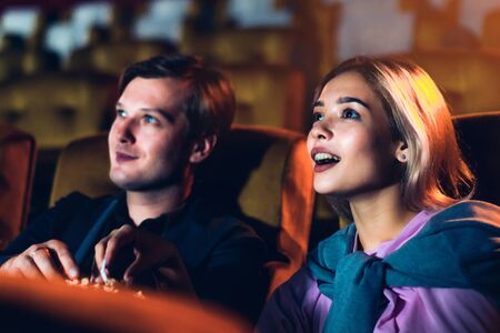 Caucasian lover enjoying to watch movie and eating popcorn together in the cinemaの写真素材