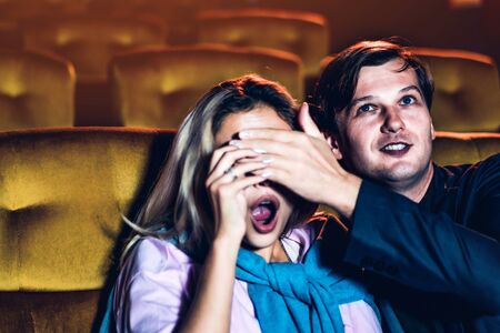 A couple watching a thriller movie in the cinema, Men use their hands to close his girlfriend's eyes.の写真素材