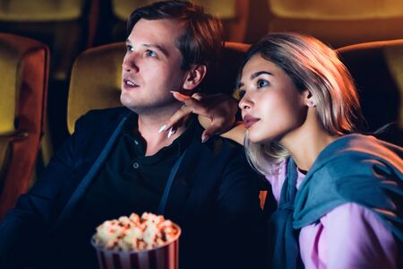 Caucasian lover enjoying to watch movie and eating popcorn together in the cinemaの写真素材