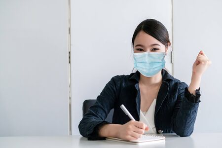 Office worker with face mask quarantine from coronavirus or COVID-19. Concept of protective working environment to reopen business and stop spreading of coronavirus or COVID-19.の写真素材