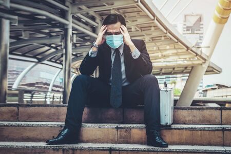 Unhappy sad business man with face mask protect from Coronavirus or Covid-19. Concept of unemployment problem caused by Coronavirus Covid-19.の写真素材