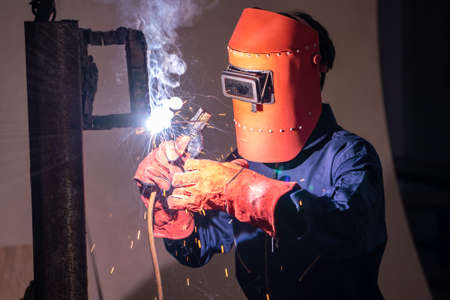 Metal welding steel works using electric arc welding machine to weld steel at factory. Metalwork manufacturing and construction maintenance service by manual skill labor concept.の写真素材