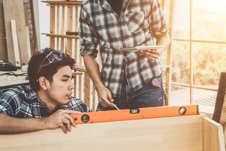 Carpenter working on wood craft at workshop to produce construction material or wooden furniture. The young Asian carpenter use professional tools for crafting. DIY maker and carpentry work concept.の写真素材