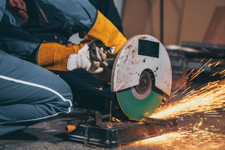 Professional mechanic man is cutting steel metal with rotating carbon blade cutter. Steel industry...