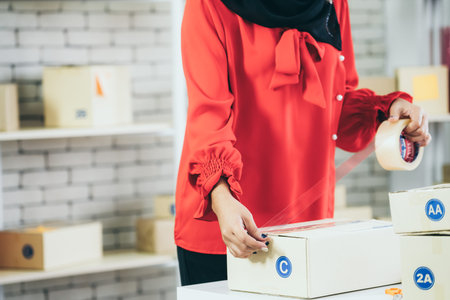 Online seller works at home office and packs shipping delivery box to customer. Small business owner...