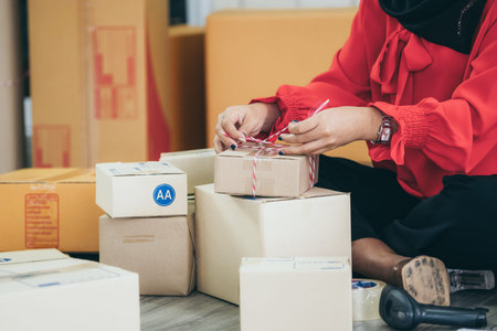 Online seller works at home office and packs shipping delivery box to customer. Small business owner or entrepreneur doing e-commerce business on the internet.の写真素材