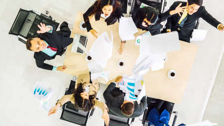 Successful business people celebrate together with joy at office table shot from top view . Young businessman and businesswoman workers express cheerful victory showing success by teamwork .の写真素材
