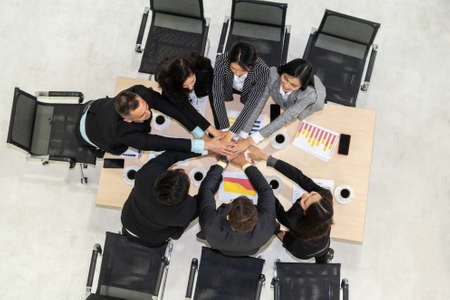 Happy business people celebrate teamwork success together with joy at office table shot from top view . Young businessman and businesswoman workers express cheerful victory showing unity and support .の写真素材