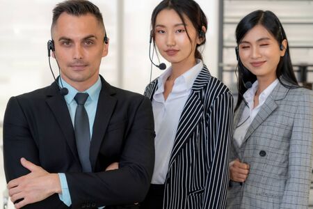 Business people wearing headset working in office to support remote customer or colleague. Call center, telemarketing, customer support agent provide service on telephone video conference call.の写真素材