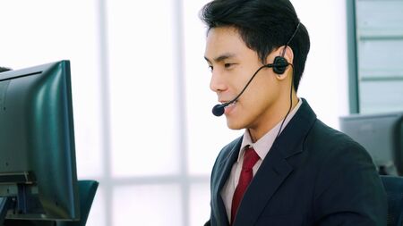 Business people wearing headset working in office to support remote customer or colleague. Call center, telemarketing, customer support agent provide service on telephone video conference call.の写真素材