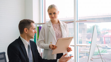 Two business people talk project strategy at office
